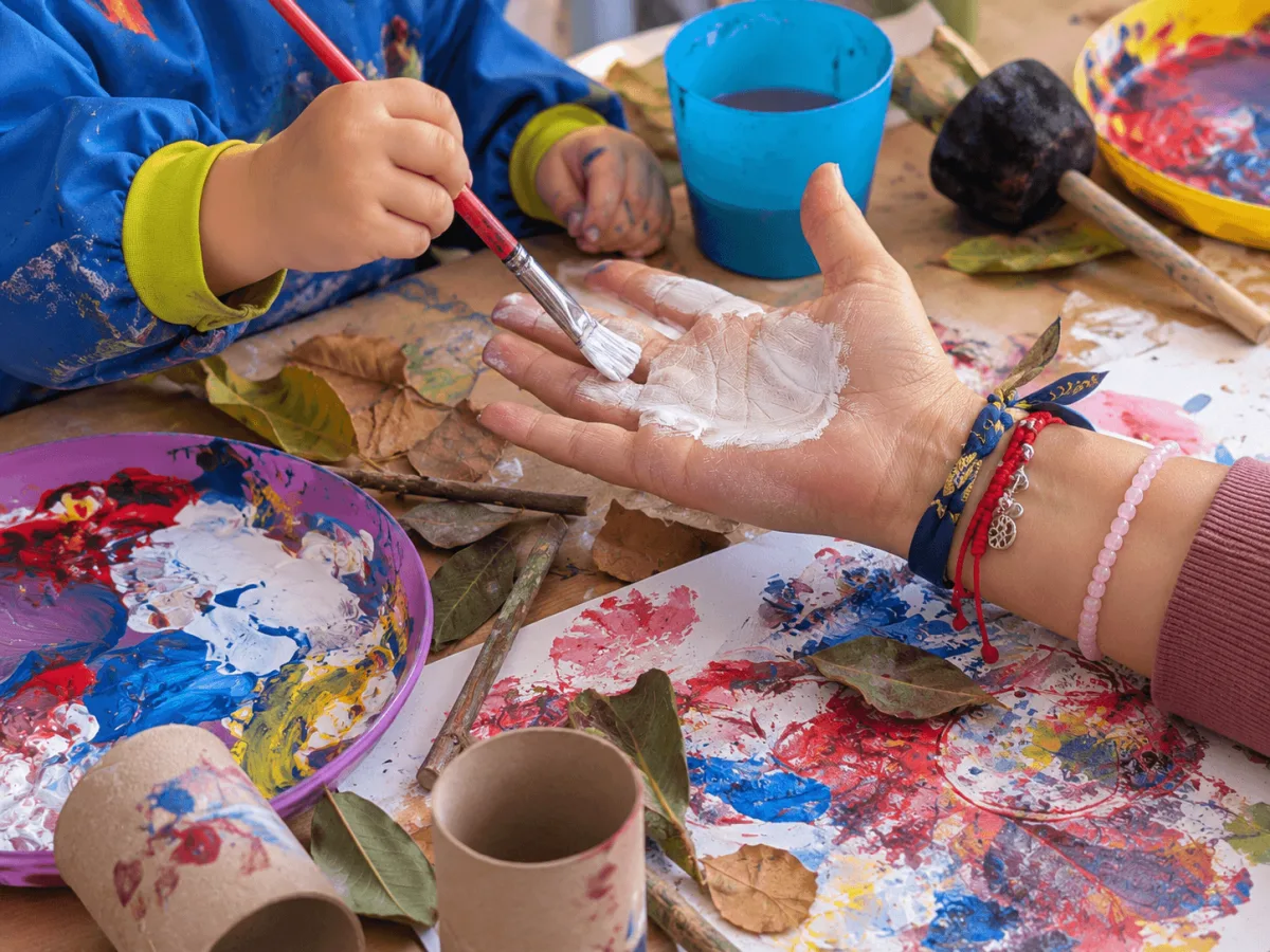Un adulto y un niño pintan juntos con pinceles y témperas durante una actividad creativa.